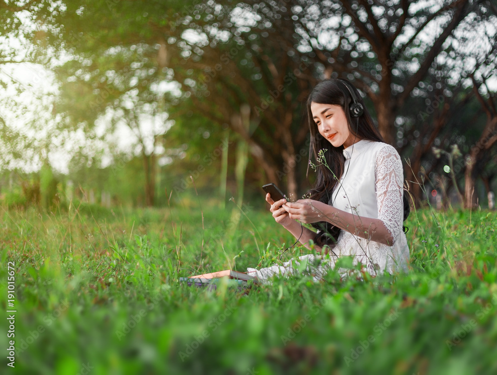 Φωτογραφία woman with headphones listening to music from smart phone and sitting in park