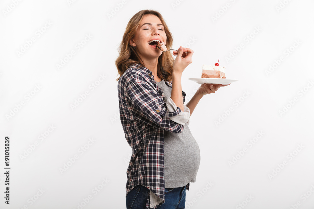 happy young pregnant woman eating cake isolated on white happy young pregnant woman eating cake isolated on white