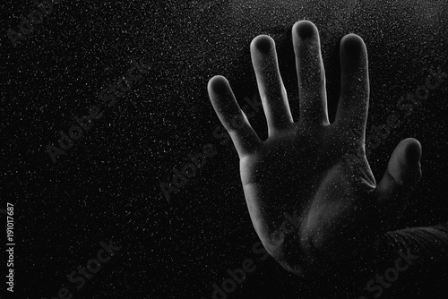 cropped shot of person touching frosted glass with palm in darkness
