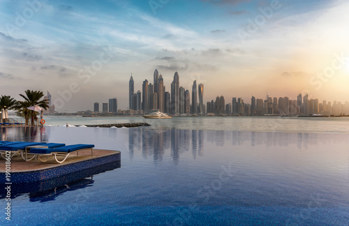 Die Skyline der Dubai Marina bei Sonnenuntergang mit Reflektionen in einem Swimming Pool