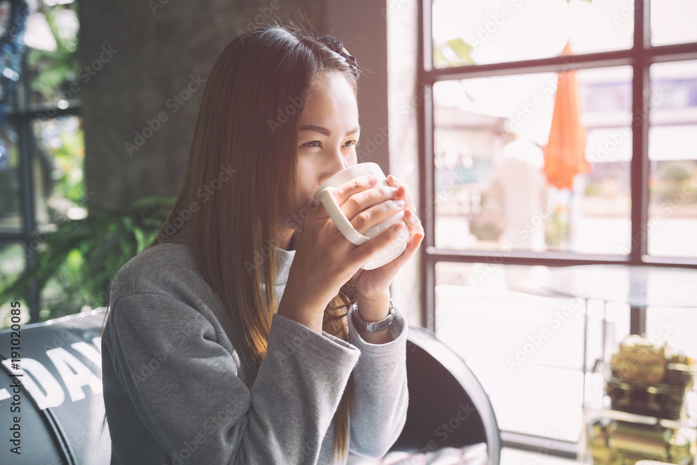 Asian women relax with coffee or relax after work in a small cozy cafe. Asian women relax with coffee or relax after work in a small cozy cafe.