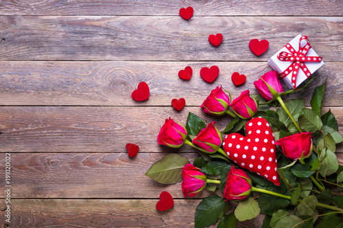Bouquet of red roses, heart and gift box on rustic wooden table