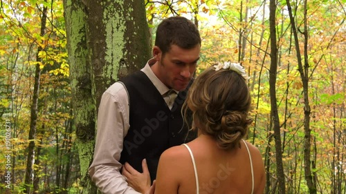 bride and groom kiss against tree in forest 4k photo