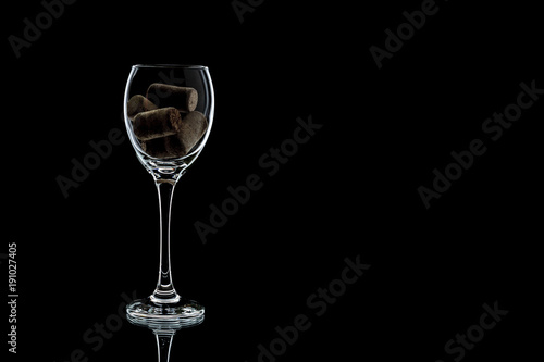 a glass of wine with cork inside completely. the glass is on a black background (isolate).