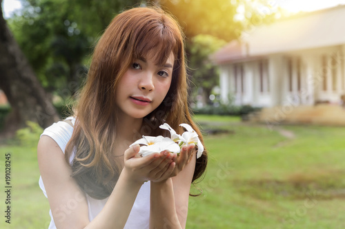 Beautiful young asian woman holding a white flowers in park