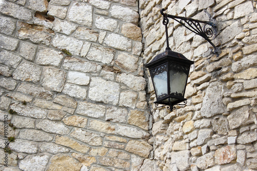 Ancient metal lantern on an old stone wall.