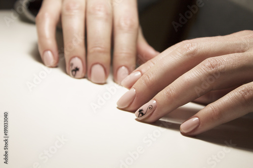 Beautiful gentle natural manicure of pink color with a painted black cat