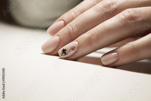 Beautiful gentle natural manicure of pink color with a painted black cat