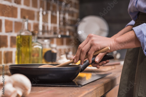 Canvas Print cropped image of woman stirring vegetables on frying pan