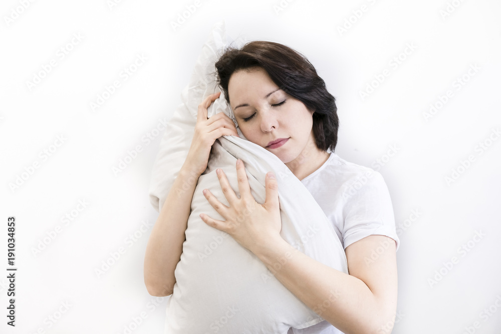 Young woman sitting on bed, hugging pillow, smiling. on white background. a girl can't Wake up Young woman sitting on bed, hugging pillow, smiling. on white background. a girl can't Wake up