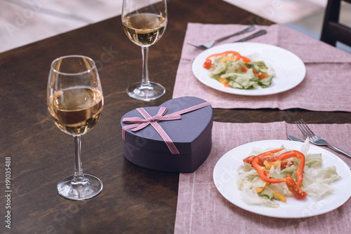 heart shaped present box with wine and food on table  st valentines day concept