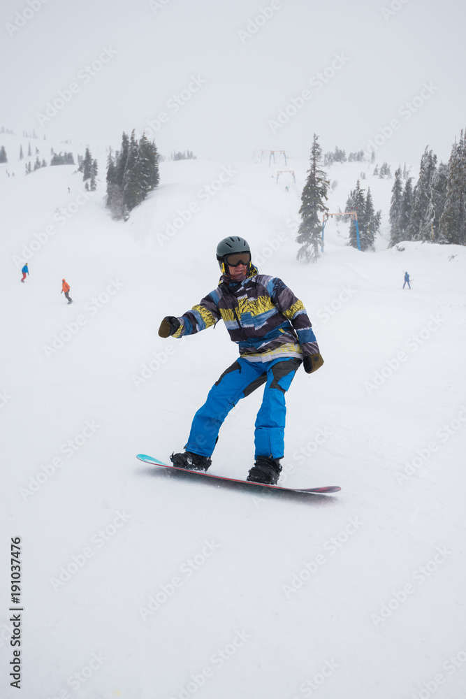 Snowboarder rides downhill in a ski resort, during a blizzard