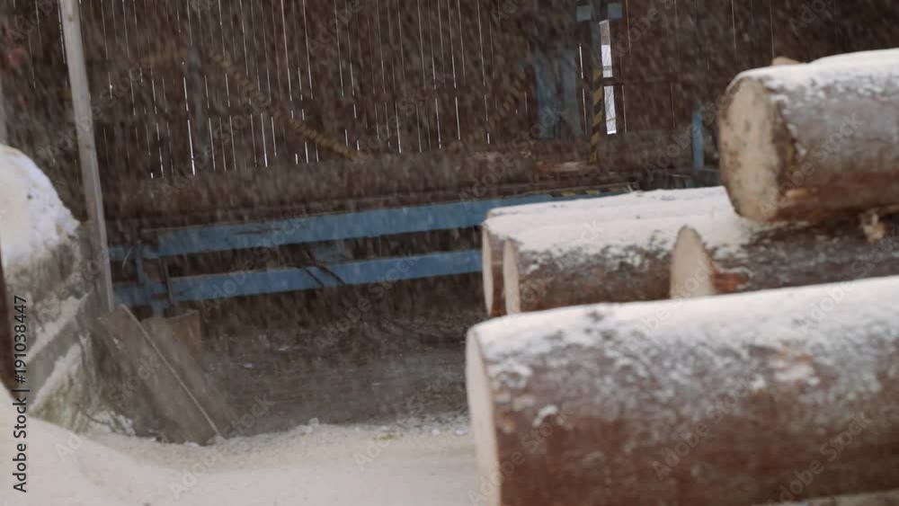 Sawdust fall on wood logs pile at sawmill, people work on background on windy cloudy day, slowmotion Sawdust fall on wood logs pile at sawmill, people work on background on windy cloudy day, slowmotion
