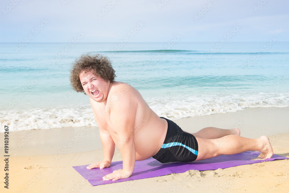 Fitness at the sea. Funny fat guy and yoga. Stock Photo | Adobe Stock