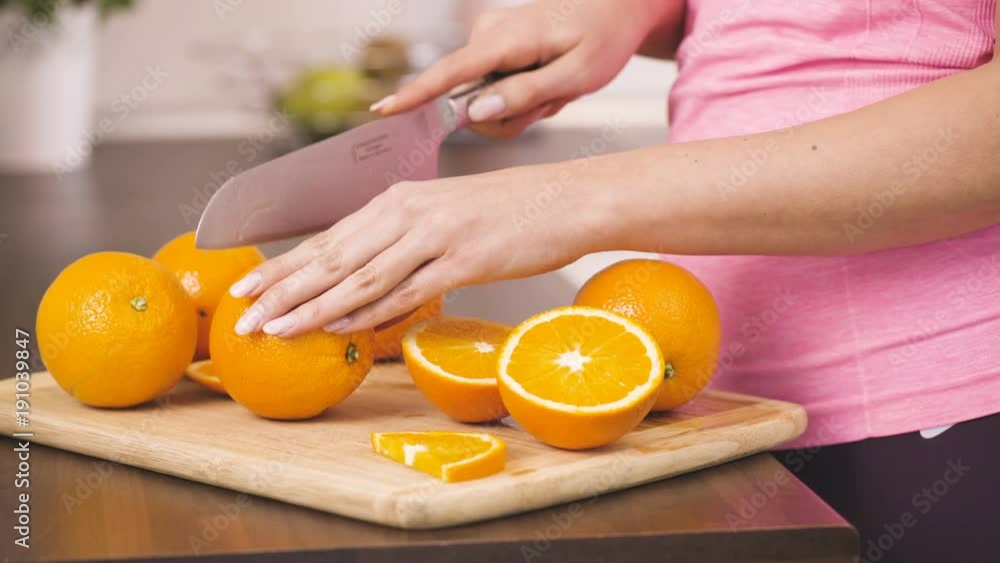 Sporty young woman cuts oranges in kitchen Sporty young woman cuts oranges in kitchen