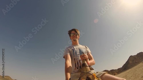 Young man riding on a camel through the desert