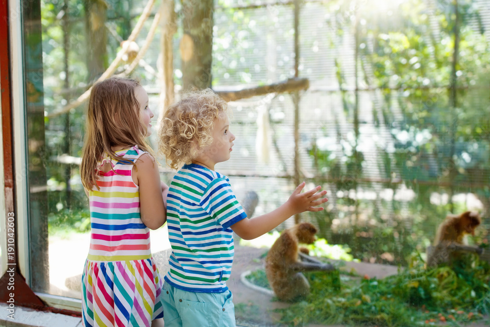 Naklejka premium Boy and girl with monkey at zoo. Kids and animals.