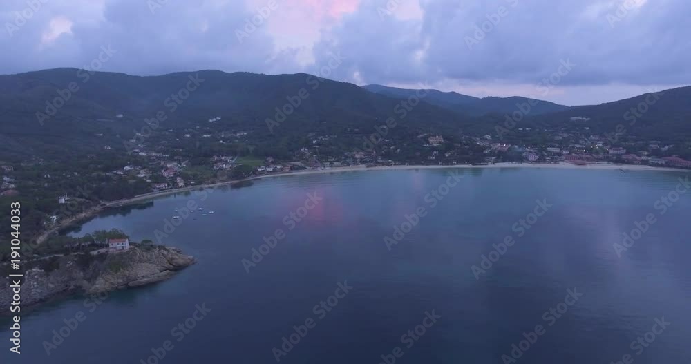 Aerial, island coast with beautiful calm sea in the evening and overcast sky Aerial, island coast with beautiful calm sea in the evening and overcast sky