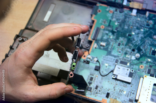 man with a screwdriver is repairing computer equipment. in his hands and details of the device. the north, south, bridge of the motherboard with usb ports and audio connectors. Quality repair.