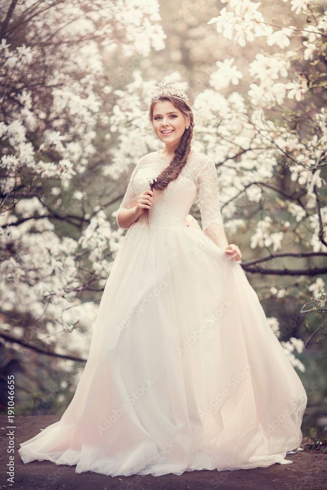 Beautiful young woman with crown in blossom magnolia garden. Spring. Beautiful young woman with crown in blossom magnolia garden. Spring.