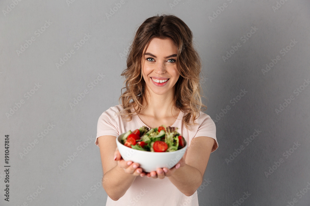 Smiling woman in t-shirt showing plate with fresh vegetables Smiling woman in t-shirt showing plate with fresh vegetables