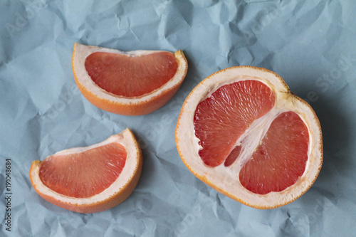 slices of juicy red grapefruit on the rumpled blue paper background texture