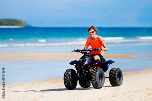 Teenager riding quad bike on beach