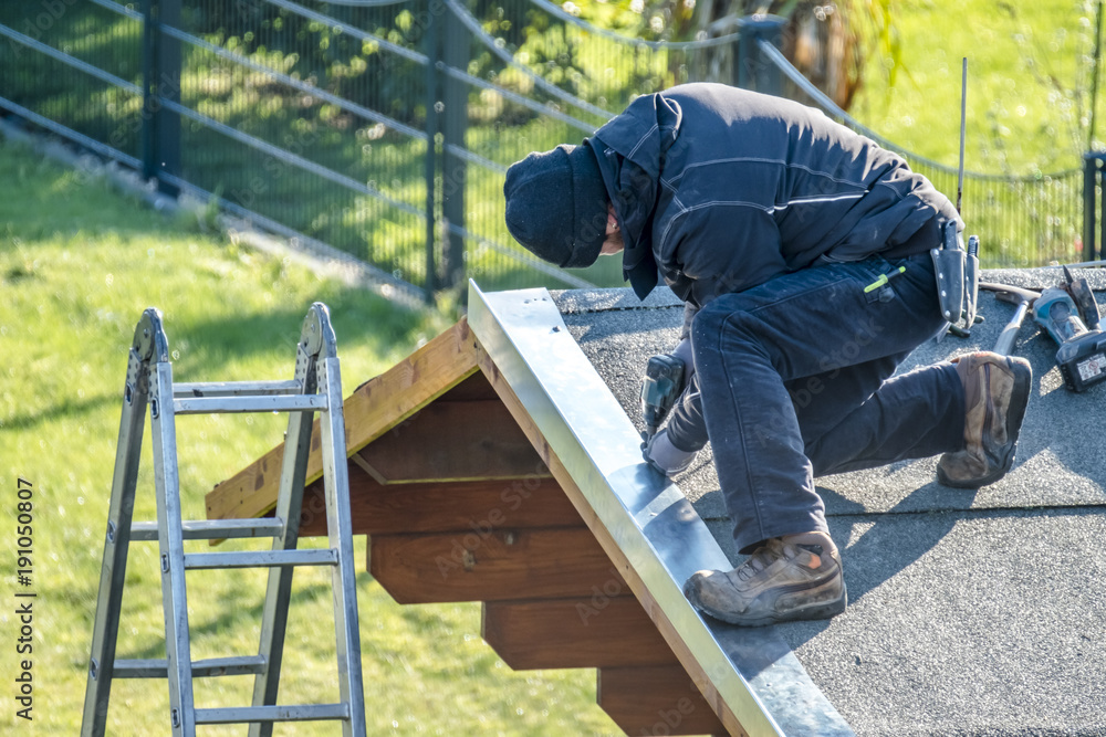 Roofer worker using battery-powered screw gun Roofer worker using battery-powered screw gun