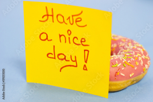 A pink glazed donut and Have a Nice Day yellow sticker note on a blue background