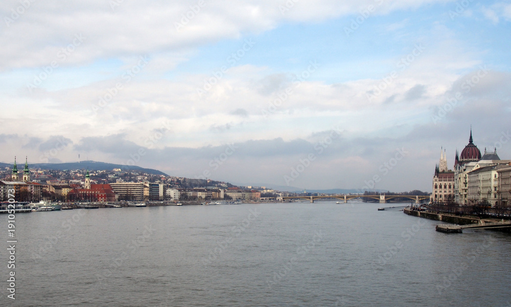 river view of budapest with historic buildings on both sides of the danube with Margaret bridge and island in the distance with blue sky and clouds