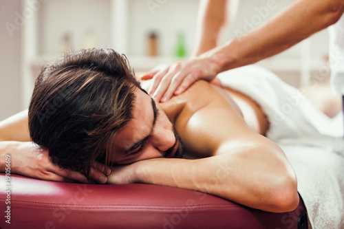 Young man is enjoying massage on spa treatment. 