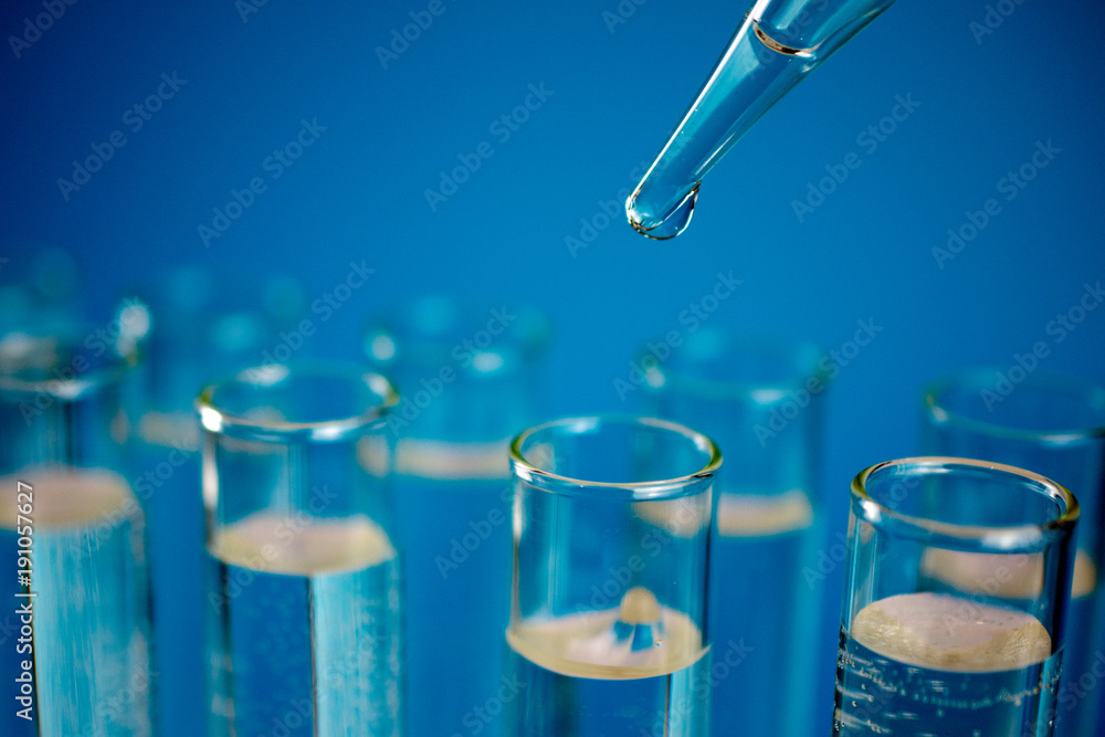 Glass test tubes with laboratory clear liquids, drops from a pipette ...