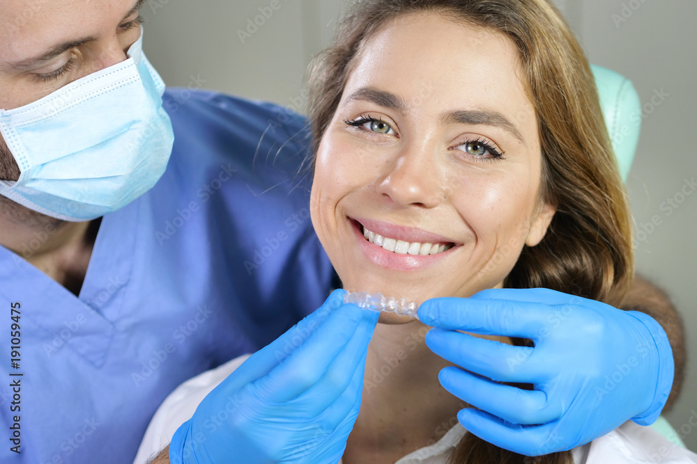 In a professional practice, a dentist checks the dentition of the patient, and she is happy with the visit, smiling, showing the perfect white teeth. Concept of: dentists, healthcare, perfect smile. In a professional practice, a dentist checks the dentition of the patient, and she is happy with the visit, smiling, showing the perfect white teeth. Concept of: dentists, healthcare, perfect smile.