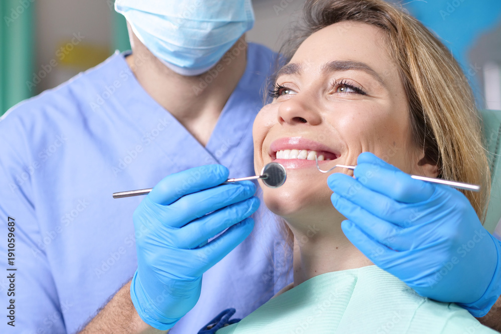 In a professional practice, a dentist checks the dentition of the patient, and she is happy with the visit, smiling, showing the perfect white teeth. Concept of: dentists, healthcare, perfect smile. In a professional practice, a dentist checks the dentition of the patient, and she is happy with the visit, smiling, showing the perfect white teeth. Concept of: dentists, healthcare, perfect smile.