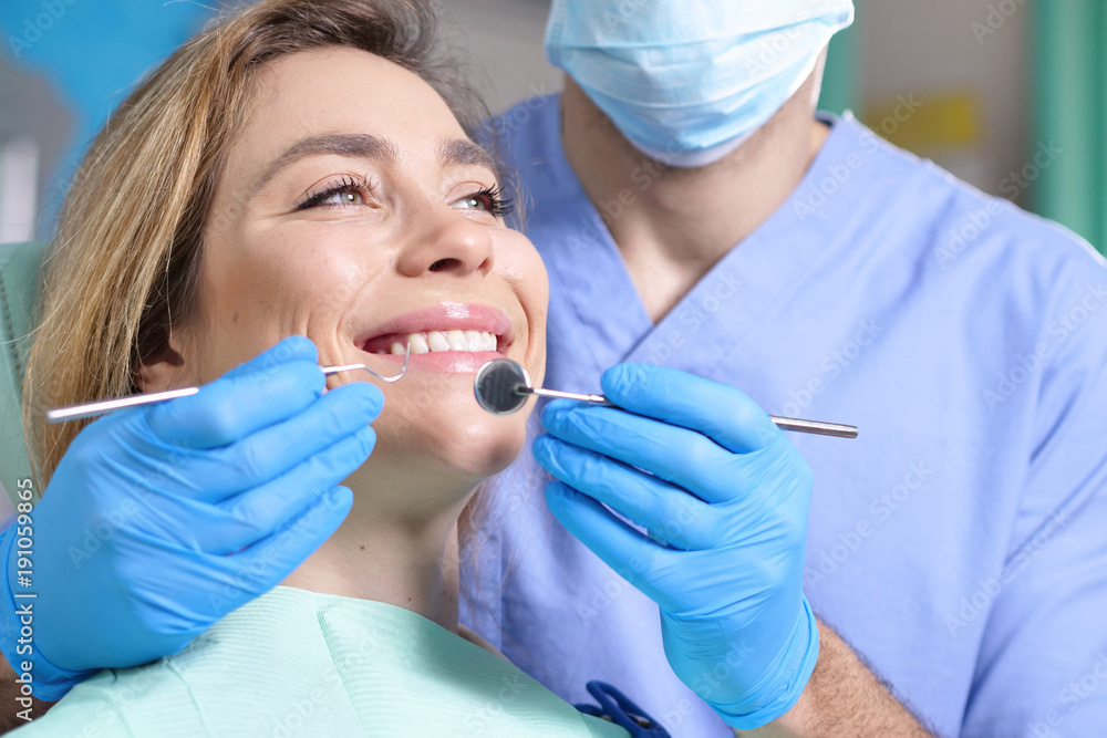 In a professional practice, a dentist checks the dentition of the patient, and she is happy with the visit, smiling, showing the perfect white teeth. Concept of: dentists, healthcare, perfect smile. In a professional practice, a dentist checks the dentition of the patient, and she is happy with the visit, smiling, showing the perfect white teeth. Concept of: dentists, healthcare, perfect smile.