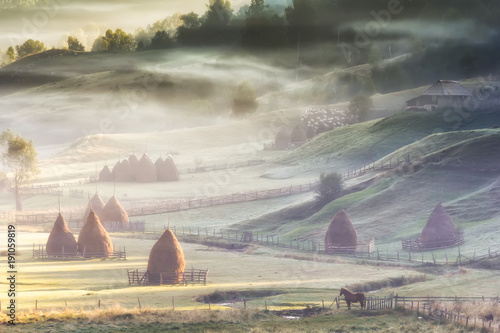 Beautiful rural mountain landscape in the sunrise light with morning fog, Fundatura Ponorului, Hunedoara County, Romania