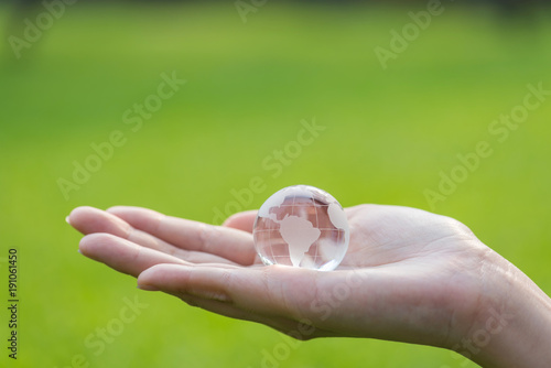 glass globe in woman hand on green grass background