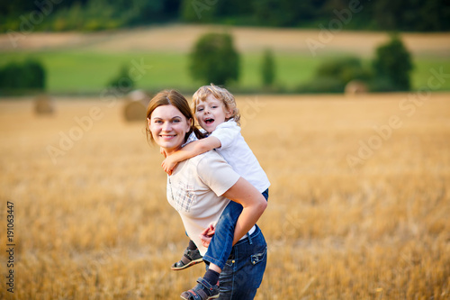 Mother holding kid boy on arms on wheat field in summer © Irina Schmidt