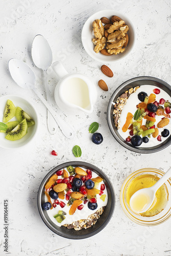 Wallpaper Mural Breakfast, rice porridge or natural yoghurt with assorted berries, fruits and nuts: kiwi, pomegranate, blueberries, almonds, dried apricots in small bowls on a light background. Top view. Copy space. Torontodigital.ca