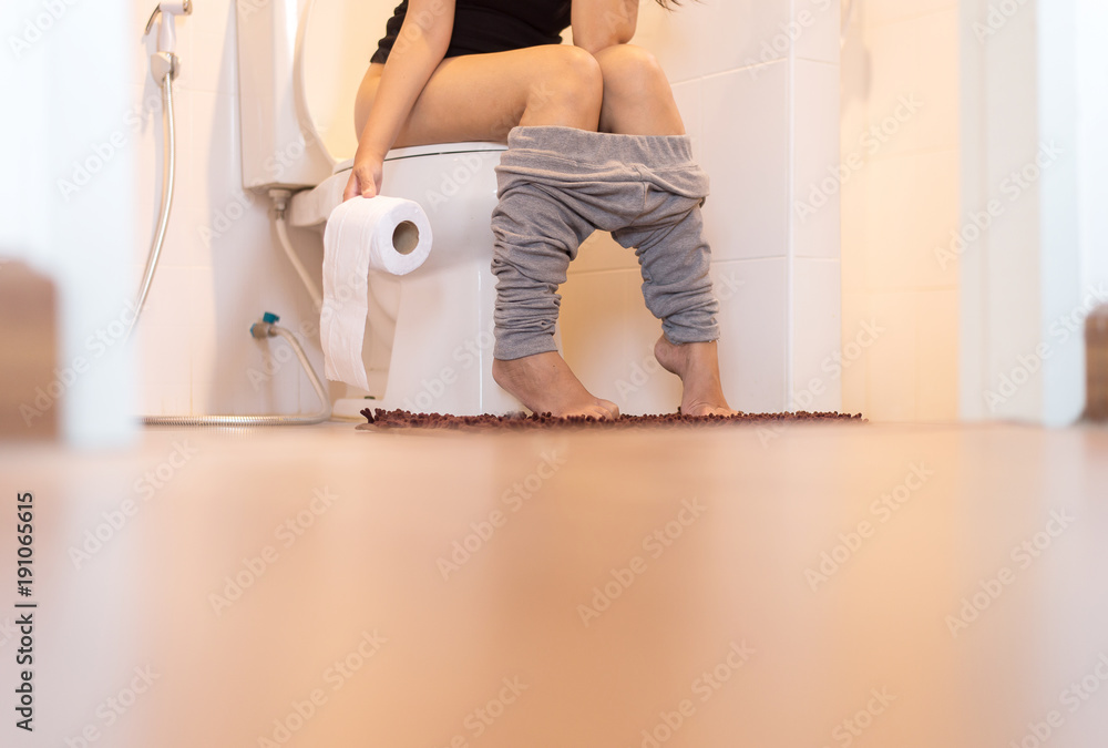 Woman using toilet after wake up in morning,Pants is hanging on her legs Woman using toilet after wake up in morning,Pants is hanging on her legs
