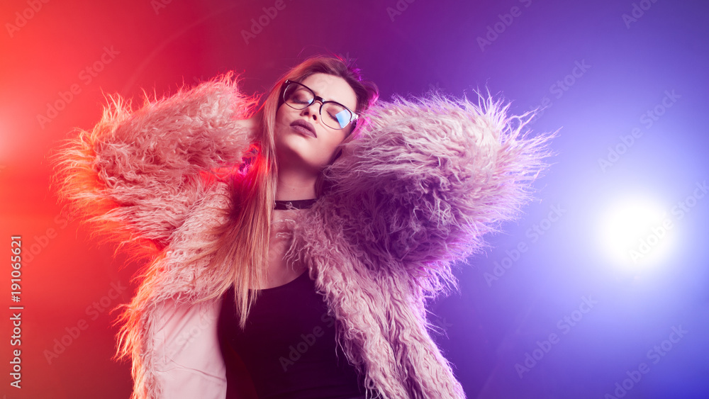 Fashionable young woman in a fluffy pink coat, neon light. Portrait of a beautiful trendy girl Fashionable young woman in a fluffy pink coat, neon light. Portrait of a beautiful trendy girl