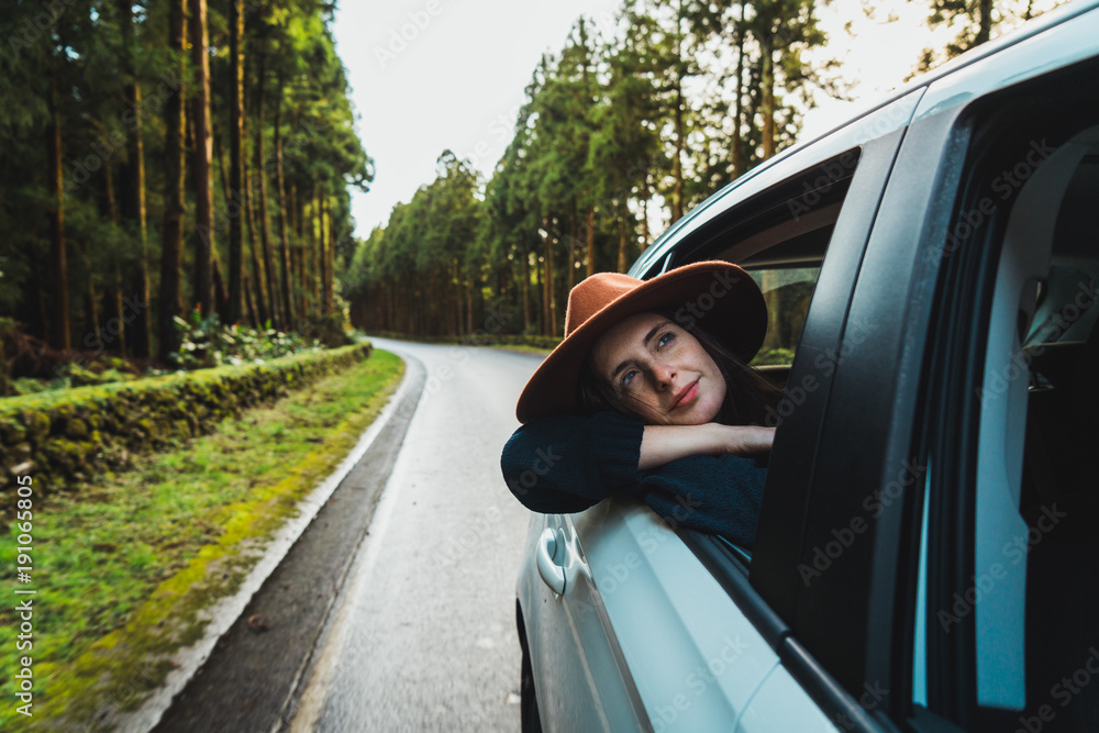 Woman hanging out of car in forest Woman hanging out of car in forest