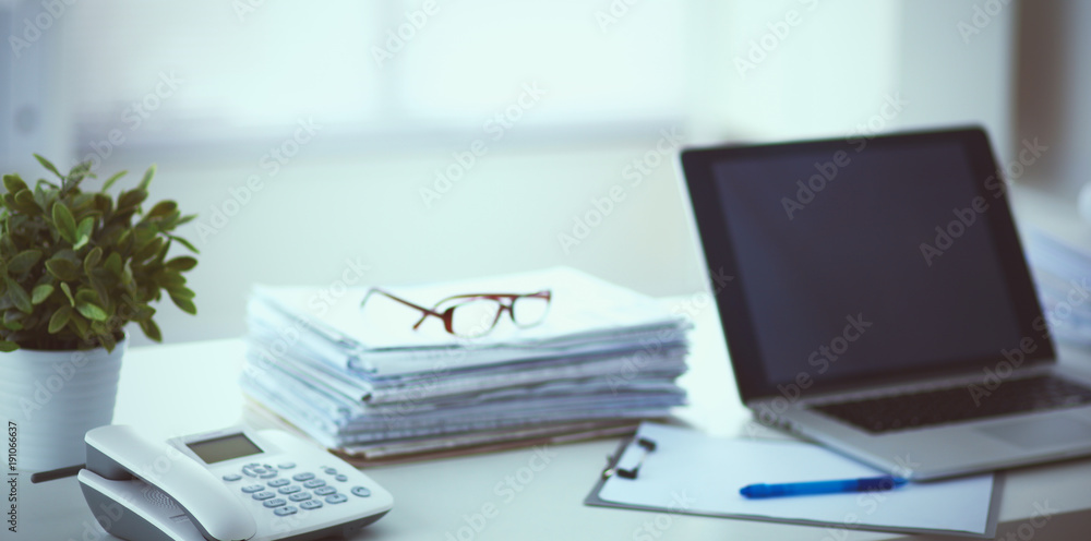 Laptop with stack of folders on table on white background Laptop with stack of folders on table on white background