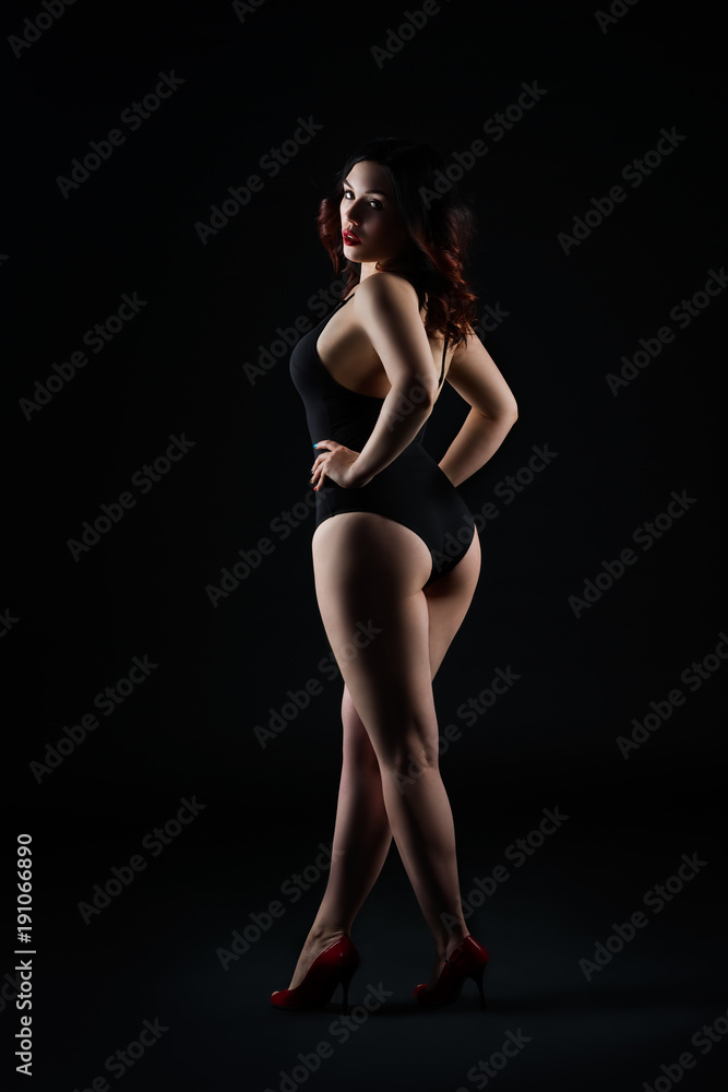 Beautiful sexy woman in bodysuit posing on black background, low key studio shot