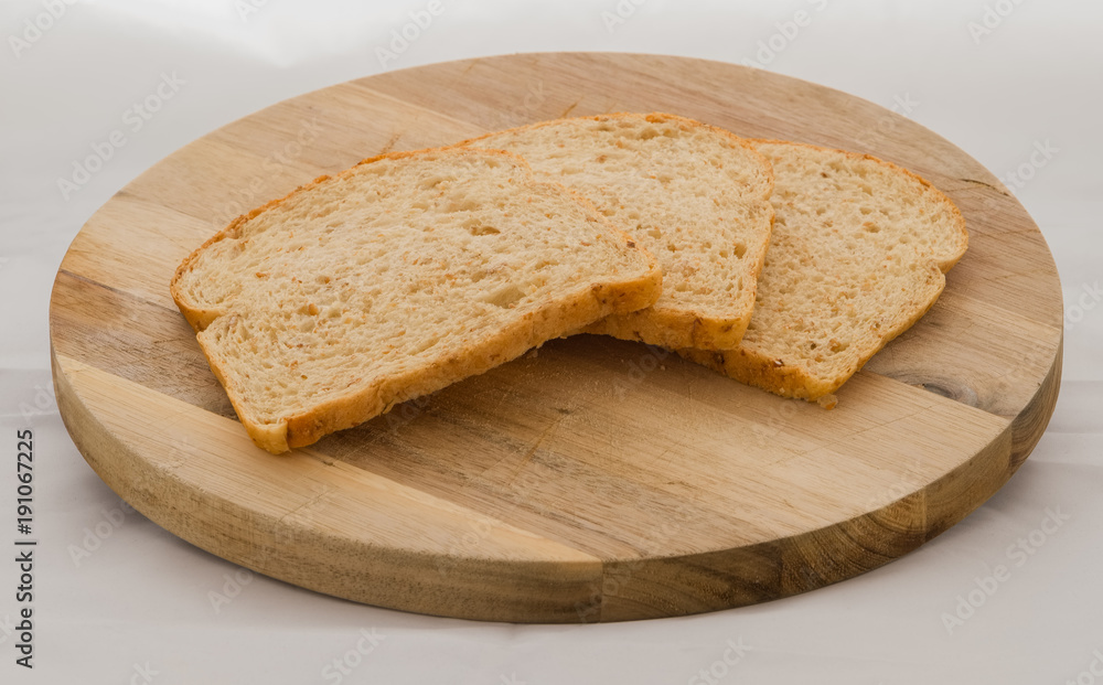 Three slices of Crumbly healthy brown bread on a wooden cutting board