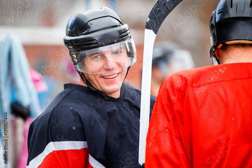 Smiling professional player waiting for substitution in ice hockey competition. Substitute ice hockey forward photo