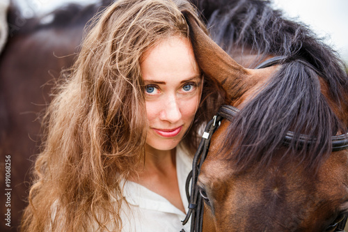 Close up portrait of young rider woman with her bay horse