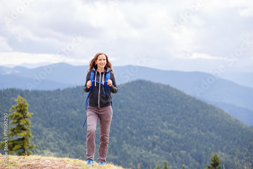 Beautiful young woman hiking in mountains with backpack. Backpacking tourism concept background with copy space