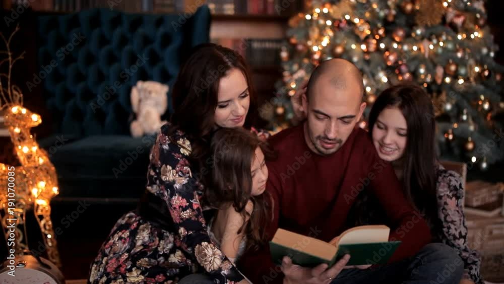 In the New Year's atmosphere, the father reads a book to his family In the New Year's atmosphere, the father reads a book to his family