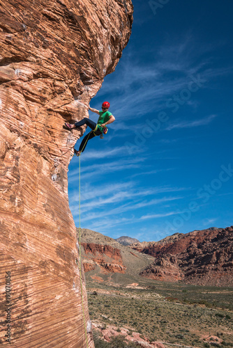 Man rock climbing red rock in desert